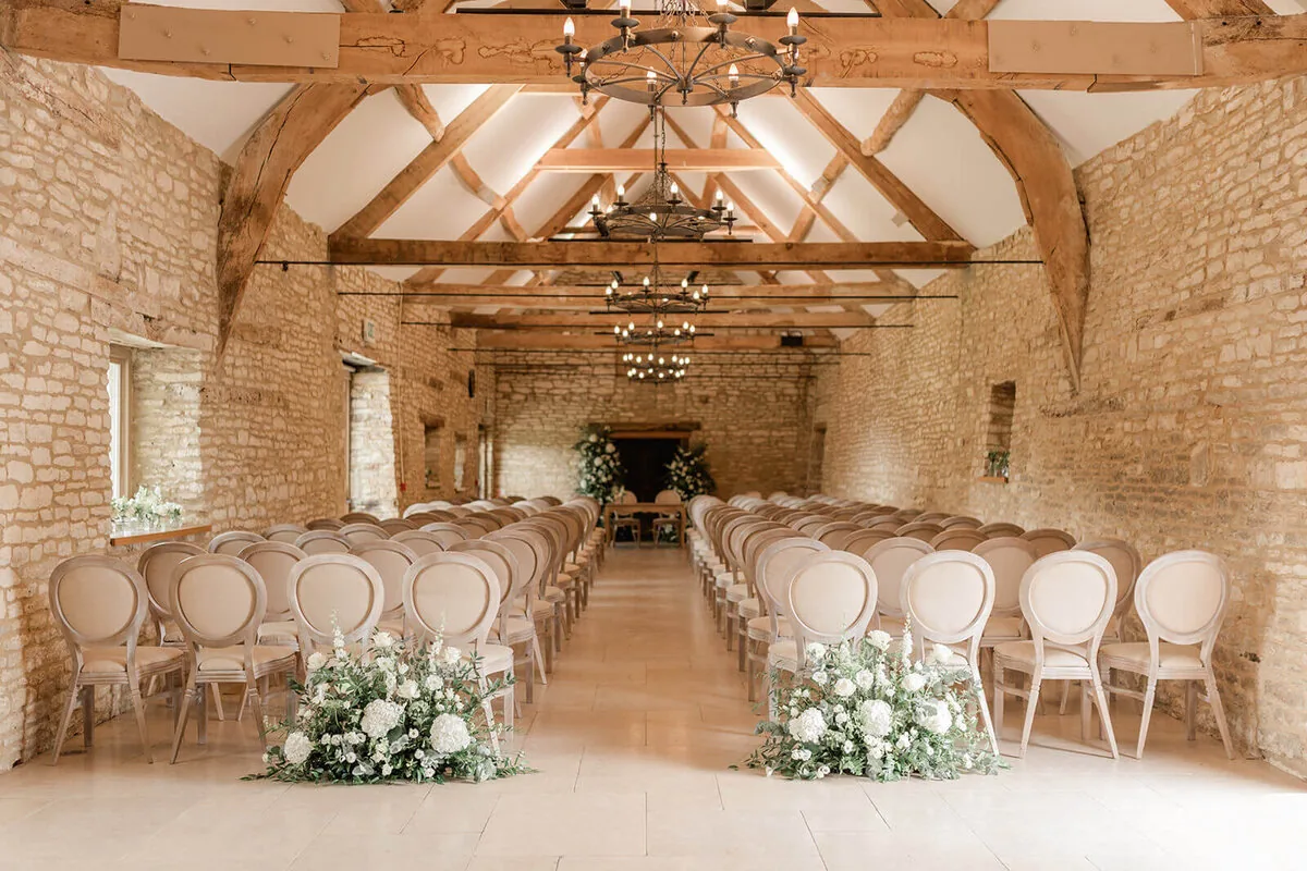 Inside the Caswell House barn dressed for a wedding ceremony with florals and Louis chairs